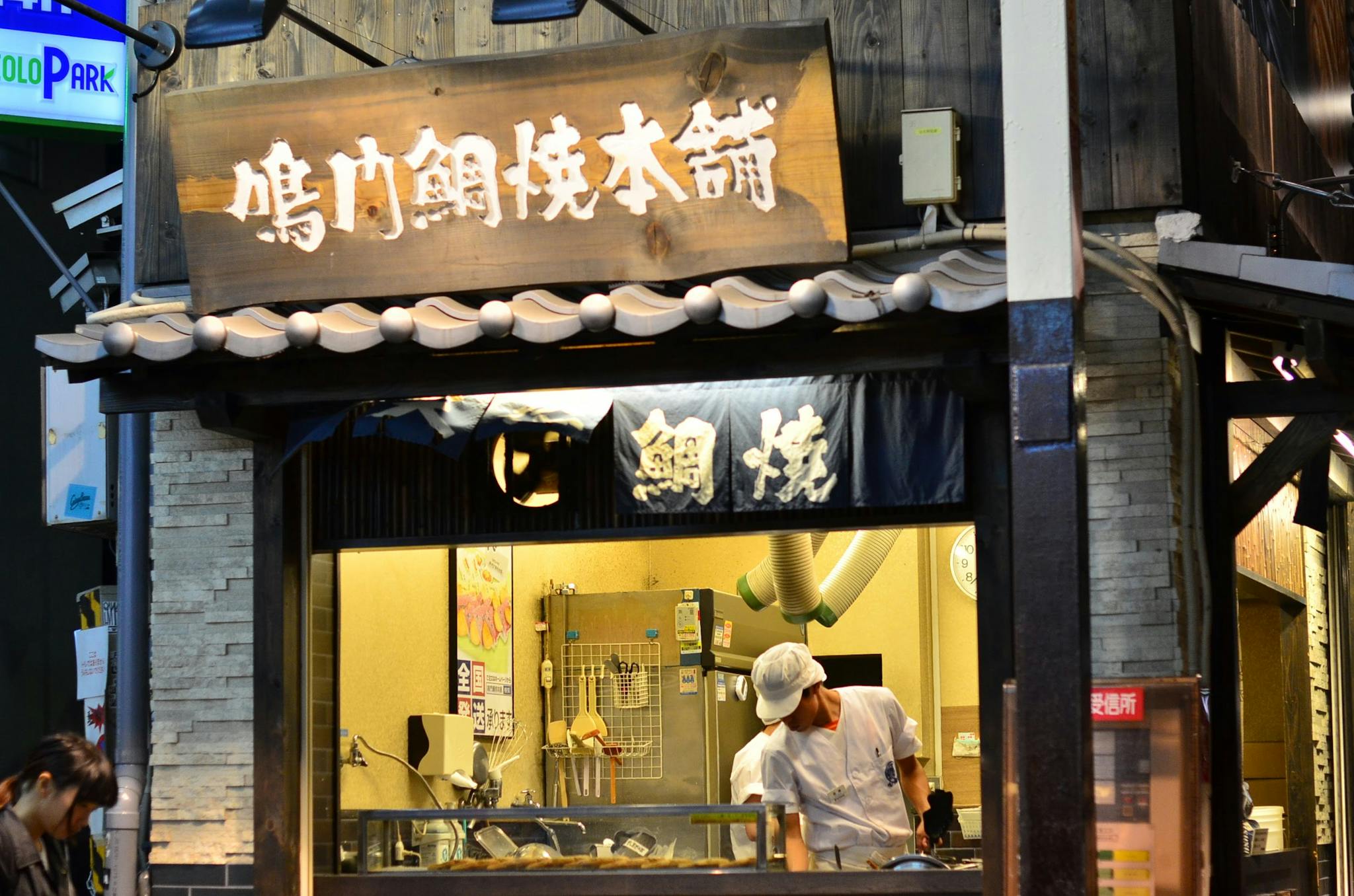 Street vendor preparing food at a traditional stall in Osaka, Japan. Cultural highlight.